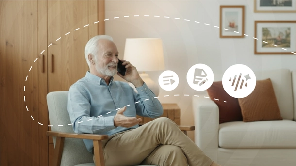 Ein älterer, zufriedener Mann sitzt und spricht über sein Mobiltelefon.